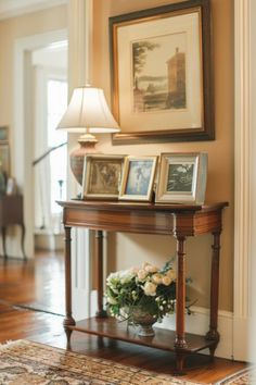 a wooden table topped with pictures and flowers on top of a hard wood floor next to a doorway