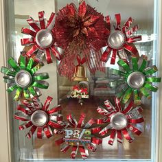 an assortment of christmas wreaths on display in a glass case with bells and candy canes