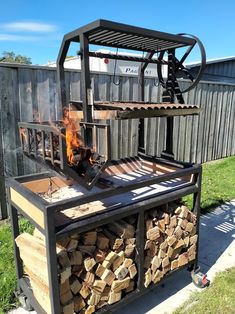 an outdoor fire pit made out of wood and metal, with flames coming from it