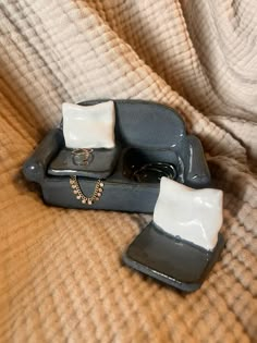 two pieces of ceramic sitting on top of a bed next to each other with jewelry in them