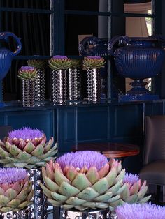 purple artichokes are displayed in front of a blue vase and other decorative items