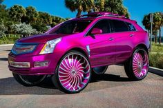 a pink cadillac parked in front of palm trees