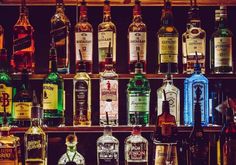 bottles of alcohol are lined up on a shelf in a liquor store, with the lights turned on