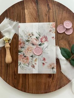 a wooden table topped with pink buttons and flowers on top of white napkins next to a green leaf