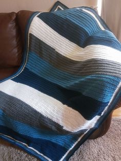 a blue and white blanket sitting on top of a brown couch