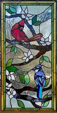 a bird sitting on top of a tree branch in front of a stained glass window