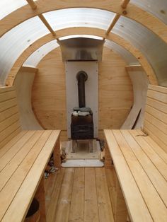 the inside of a wooden cabin with benches and a stove in it's center