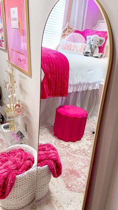 a mirror that is reflecting a bed in a room with pink accessories on the floor