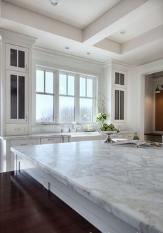 a large kitchen with marble counter tops and white cabinets