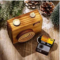 a wooden camera sitting on top of a table next to a pine cone and christmas tree