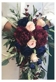 a bridal bouquet with red, white and blue flowers is held by a woman