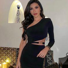 a beautiful woman in a black dress posing for the camera with her hands on her hips