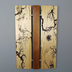 two pieces of wood with black and white designs on them are hanging on the wall