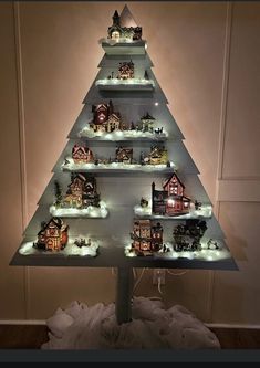 a christmas tree made out of shelves filled with small houses and snowflakes