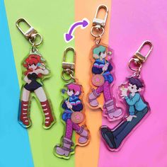 three keychains with cartoon characters on them, one is pink and the other is blue