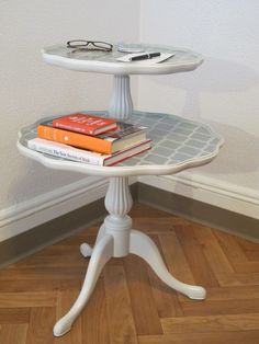 a white table with books and glasses on it in the middle of a wooden floor