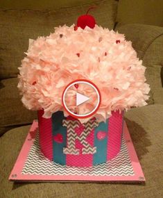 a cupcake with pink flowers in it sitting on top of a cardboard box that says happy valentine's day