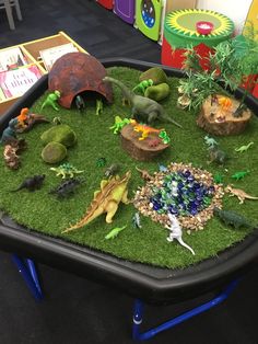 an assortment of toy dinosaurs on display in a classroom