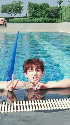 a boy in a swimming pool with his hand on the edge