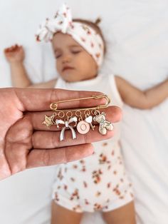 a person holding a baby's name charm in their hand with a white background