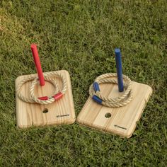 two wooden coasters with ropes on them sitting in the grass, one has a red and blue umbrella