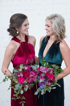 two women standing next to each other holding bouquets