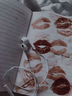 an open notebook with lipstick drawn on it and headphones attached to the book's earbuds