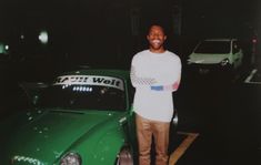 a man standing next to a green car