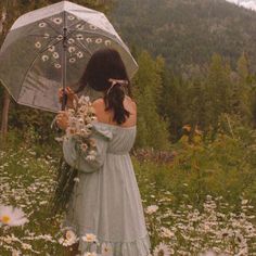 a woman holding an umbrella standing in a field full of daisies and wildflowers