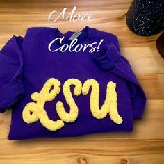 a purple shirt with the letters csu and u on it sitting on a wooden table