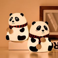 two panda lamps sitting on top of a white shelf next to a framed photo and a wooden frame