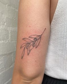 a woman's arm with an olive branch tattoo on the left side of her arm