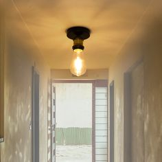 an open door leading to a hallway with a light bulb hanging from it's ceiling