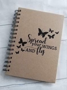 a spiral notebook with the words spread your wings and fly written in black on it