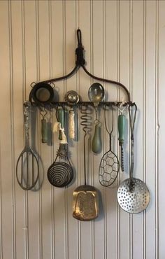 a rack with various kitchen utensils hanging from it's side on a wall