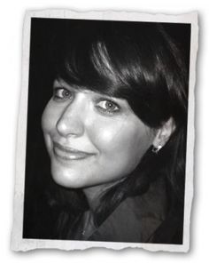 a black and white photo of a woman with dark hair smiling at the camera,