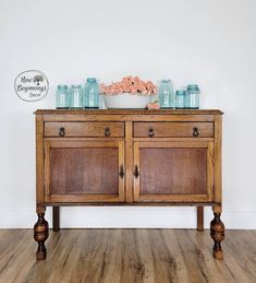 a wooden cabinet with jars and flowers on top