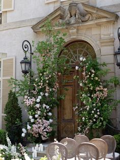 there are many chairs in front of the door and some flowers on the side of the building