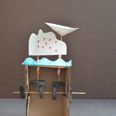 a cardboard box with some sort of boat on it's roof and wheels in the front