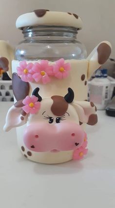 a cow with flowers on its head next to a jar