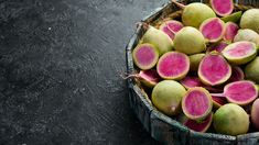 a basket filled with lots of ripe figs on top of a black countertop