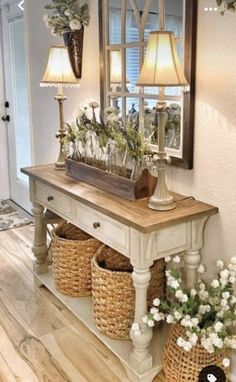 a table with baskets and flowers on it in front of a mirror that is reflecting the light