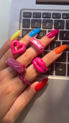 a woman's hand with five different colored nail polishes on her fingers next to a laptop keyboard