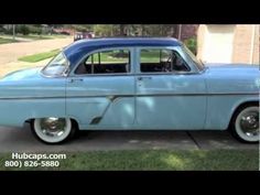 an old blue car parked in front of a house