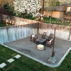 an outdoor patio area with lights strung on the fence and lawn furniture in the back yard