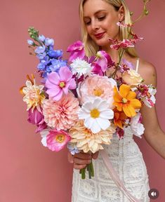 a woman holding a bouquet of colorful flowers