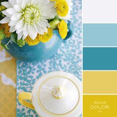 a teapot with flowers in it sitting on a table next to a blue vase