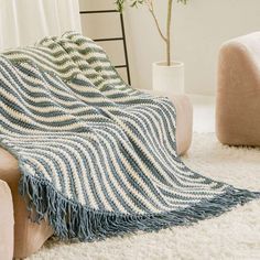 a blue and white striped blanket sitting on top of a couch next to a chair