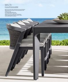 an outdoor dining table with chairs next to the ocean