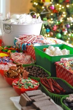 a table filled with lots of different types of candy and candies next to a christmas tree